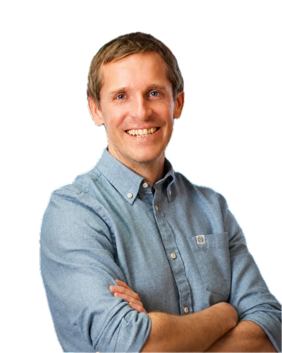 Steen Stones, smiling, with his arms folded, in a blue shirt.